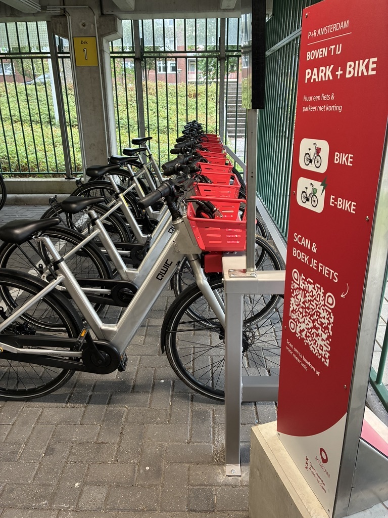 De rode zuil 'Park + Bike' met QR-code naast de fietsen met rode manden