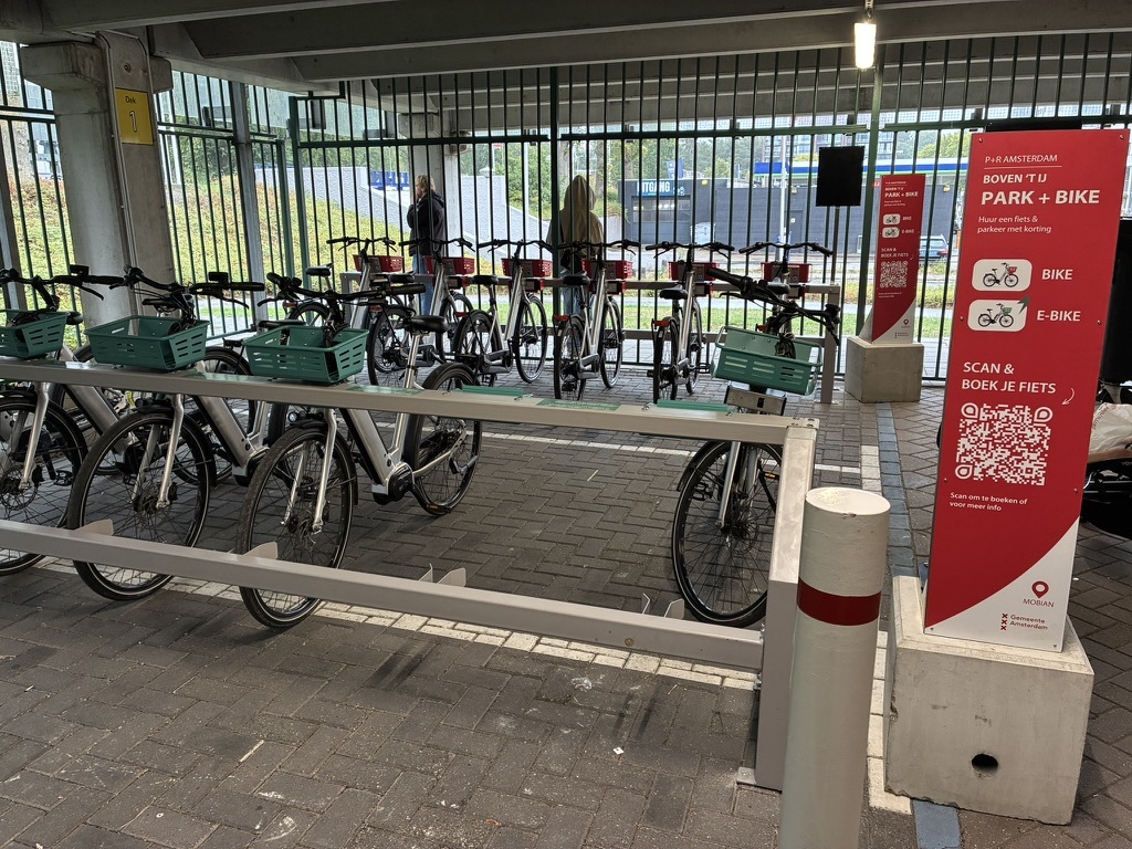 Fietsenrekken op P+R Boven 't Y met groene manden (e-bikes) en de rode P+R-zuil met QR-code